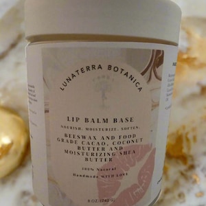 May include: A cylindrical jar of Lunaterra Botanica lip balm base. The label features text including "Lip Balm Base" and ingredients like beeswax and shea butter. The jar is 8 oz (240 g) and has a light beige lid.