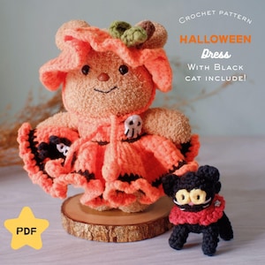 May include: A crochet pattern for a tan bear wearing an orange ruffled dress with a skull accent and a small black cat. The text reads: CROCHET PATTERN HALLOWEEN Dress WITH Black CAT INCLUDE! PDF. The bear has a green leaf on its head.