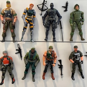 May include: Collection of eight action figures, each depicting a soldier in various military uniforms. The figures are in different poses and feature detailed accessories like weapons and gear. The color palette includes greens, browns, and blacks.