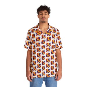 May include: A short-sleeved button-down shirt featuring a repeating pattern of abstract, star-like shapes in vibrant red, yellow, and blue colours against a white background. The shirt has a classic collar and a straight hemline.
