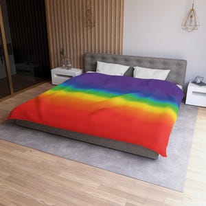 May include: A bed featuring a duvet cover with a horizontal gradient pattern transitioning through the colors of the rainbow, starting with purple at the top, followed by blue, green, yellow, orange, and ending with red at the bottom edge.