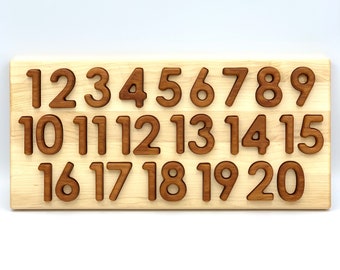 May include: Wooden number puzzle with numbers 1 through 20 cut out. The numbers are arranged in three rows on a light brown wooden board.