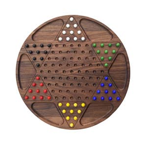 Puede incluir: Un tablero de juego de madera con un área de juego en forma de estrella. El tablero tiene seis puntos, cada uno con un color diferente de canicas. Los colores son blanco, negro, rojo, azul, verde y amarillo.