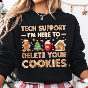 May include: Black sweatshirt with a gingerbread cookie design. The text reads "TECH SUPPORT - I'M HERE TO - DELETE YOUR COOKIES" with gingerbread man, Christmas tree, and gingerbread house graphics.