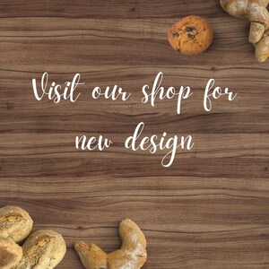 May include: A wooden surface with the text 'Visit our shop for new design' in white. There are three pieces of bread and a cookie on the surface.