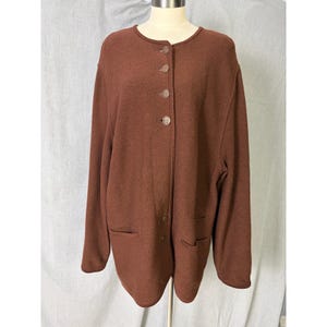 May include: A brown cardigan with a round neckline and button closure. The long-sleeved jacket has two front pockets and is displayed on a mannequin. The fabric appears to be a soft, knit material.
