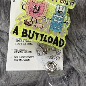 May include: A humorous badge reel with a cartoon colon and medical machine. Text reads "WHAT DOES A COLONOSCOPY COST? A BUTTLOAD." The badge reel is yellow with glitter and has a clear plastic clip.