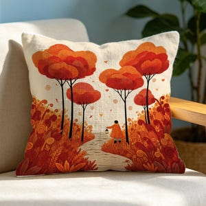May include: A square throw pillow featuring an off-white background with a printed illustration of a person in an orange coat walking along a path through a forest of stylized orange and red trees, surrounded by dense, swirling autumn foliage.