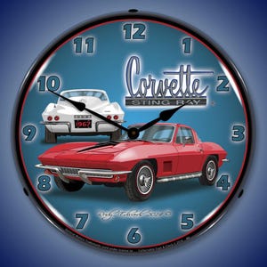 Pode incluir: Relógio de parede redondo com um Corvette Sting Ray vermelho e um Corvette branco. O mostrador do relógio é azul com algarismos pretos e o logotipo da Corvette. O relógio tem uma moldura de metal preta.