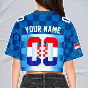 May include: Blue cropped jersey with a checkered pattern and the text "YOUR NAME" across the back. The jersey features the Croatian flag colors and emblem, with the number "00" prominently displayed. A Croatian flag is on the right sleeve.
