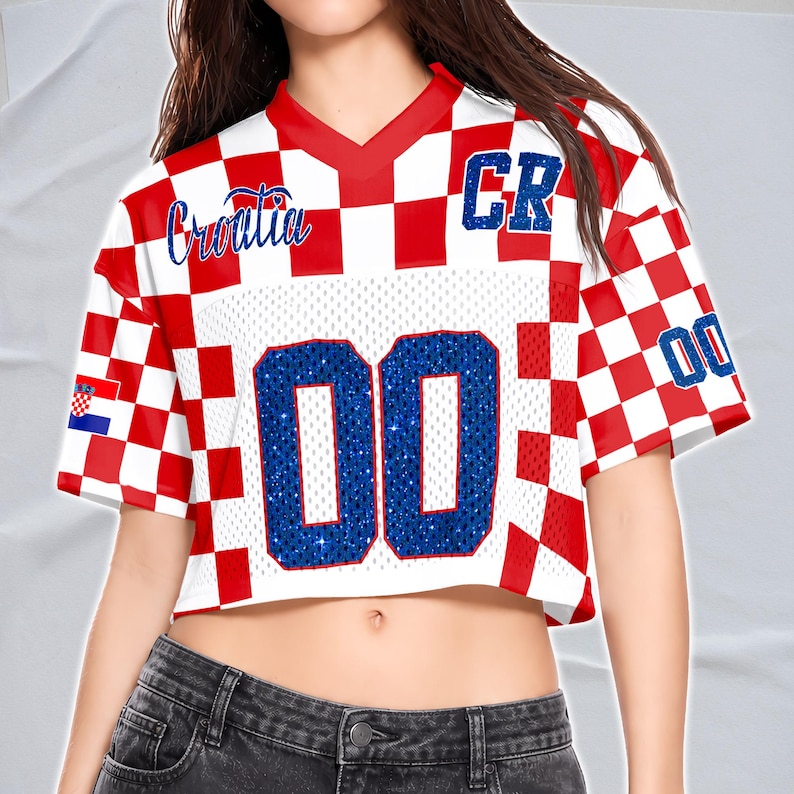May include: Cropped white and red checkered jersey with the word "Croatia" in blue script. The jersey has the number "00" in blue glitter and the letters "CR" on the shoulder.