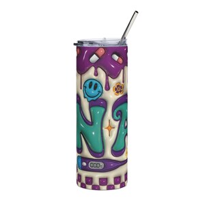 May include: A tall, insulated tumbler with a stainless steel straw. The design features a purple, teal, and cream color scheme with a smiley face, pills, and the word "NA" in a graffiti style. The bottom has a checkered pattern.