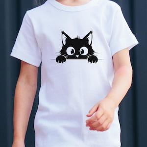 May include: White t-shirt featuring a black cat graphic. The cat's head and paws peek over a horizontal line, with large, wide eyes. The design is simple and playful, suitable for children's apparel.