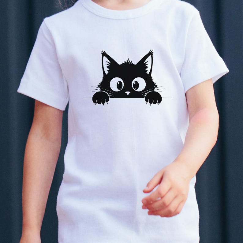 May include: White t-shirt featuring a black cat graphic. The cat's head and paws peek over a horizontal line, with large, wide eyes. The design is simple and playful, suitable for children's apparel.