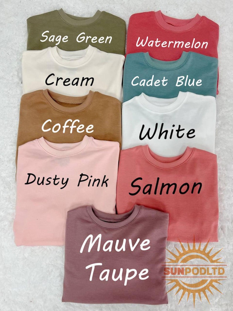 Puede incluir: Una colecci&oacute;n de nueve sudaderas de cuello redondo en varios colores, incluyendo verde salvia, sand&iacute;a, crema, azul cadete, caf&eacute;, blanco, rosa empolvado, salm&oacute;n y topo malva. Cada sudadera tiene el nombre de su color impreso en una fuente clara.