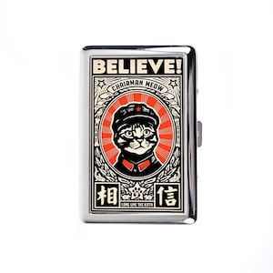 Pode incluir: Um porta-cigarros de metal prateado com um gráfico de um gato usando um chapéu e uma estrela vermelha. O texto "BELIEVE! CHAIRMAN MEOW" está acima do gato, com caracteres chineses e "LONG LIVE THE KITTY" abaixo.