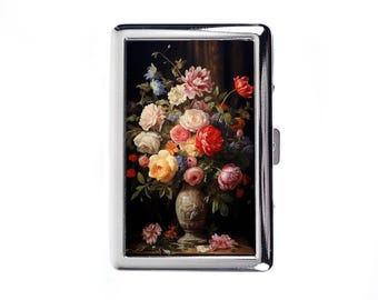 Pode incluir: Um porta-cigarros prateado com uma pintura de natureza morta floral. A obra de arte apresenta um buquê de rosas, peônias e outras flores em tons de vermelho, rosa, amarelo e branco, sobre um fundo escuro.