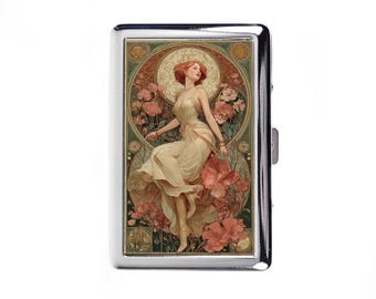 Pode incluir: Um porta-cigarros prateado com uma ilustração em estilo Art Nouveau. A obra de arte retrata uma mulher em um vestido esvoaçante em meio a flores cor-de-rosa. O porta-cigarros tem uma superfície brilhante e um fecho seguro.