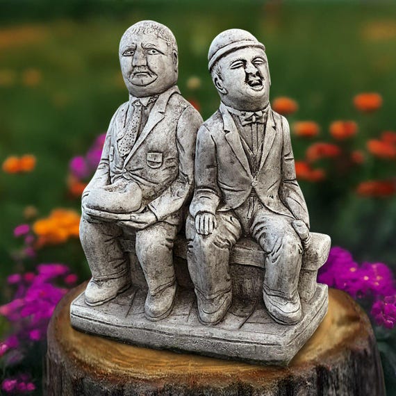 Hand-sculpted cement comedy duo figures that look like they belong in a quirky art gallery rather than a garden center — genuinely one-of-a-kind heavy art objects.