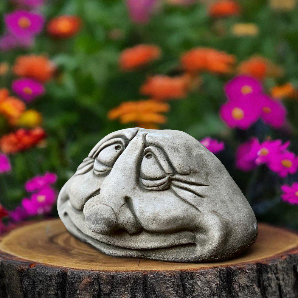 コンクリート製の面白い顔の彫像。遊び心のある石の置物。屋外の庭の