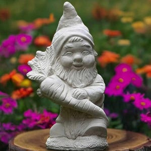 Puede incluir: Estatua de gnomo de jardín de hormigón gris claro que sostiene una zanahoria grande. El gnomo tiene una larga barba blanca y un gorro puntiagudo. Está sonriendo. La estatua está sobre una base de madera, con un colorido jardín de flores al fondo.