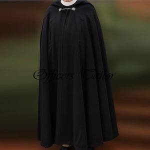 May include: A floor-length black hooded cloak featuring a white clerical collar at the neckline and a decorative silver-toned metal clasp closure. The garment has vertical slit pockets on the front and the text Officers Tailor is visible.