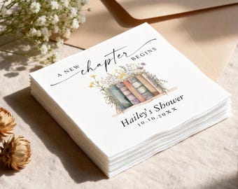 May include: A stack of white paper napkins with the text "A New Chapter Begins" in black script. The napkins feature a watercolor illustration of books and flowers, with the text "Hailey's Shower" and a date below.