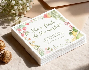 May include: A stack of white paper napkins with the text "She's fresh off the market!" and "Charlotte's Bridal Shower September 15, 20XX". The napkins are decorated with watercolor illustrations of fruits and flowers.