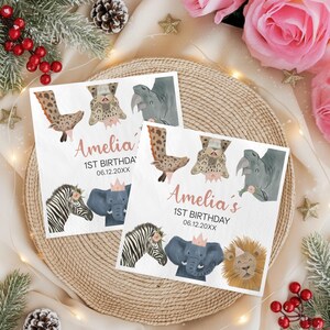May include: Two white paper napkins with watercolor illustrations of safari animals, including a zebra, elephant, and lion. The napkins are personalized with the name "Amelia" and the text "1st Birthday" in pink script.