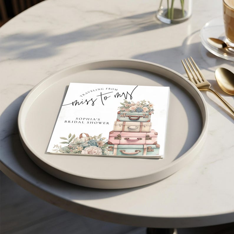 May include: A square invitation card with the text "Traveling from Miss to Mrs" and "Sophia's Bridal Shower". The card features a watercolor illustration of stacked vintage suitcases in pastel colors, topped with flowers.