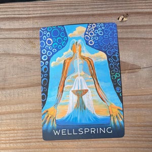 May include: A rectangular card with the word "WELLSPRING" at the bottom. The card features a blue background with white and blue circles. The image depicts a person with orange arms and a white waterfall.