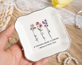 May include: A white ceramic trinket dish with a gold rim, featuring floral illustrations and the names Amity, Coral, and Maria. The text reads, "If friends were flowers I would pick you."