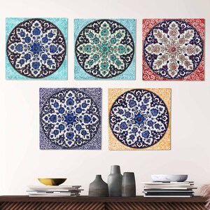 May include: Five square wall art pieces with circular floral designs. The designs feature blue, white, and red floral patterns on backgrounds of light blue, teal, red, purple, and yellow. The art is displayed above a wooden shelf.