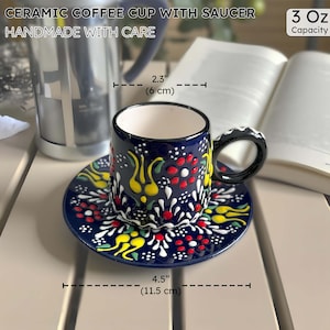 May include: A ceramic coffee cup and saucer set. The cup and saucer are navy blue with a colorful floral pattern. The cup is 2.3 inches (6 cm) in diameter and the saucer is 4.5 inches (11.5 cm) in diameter. The set is handmade and holds 3 oz.