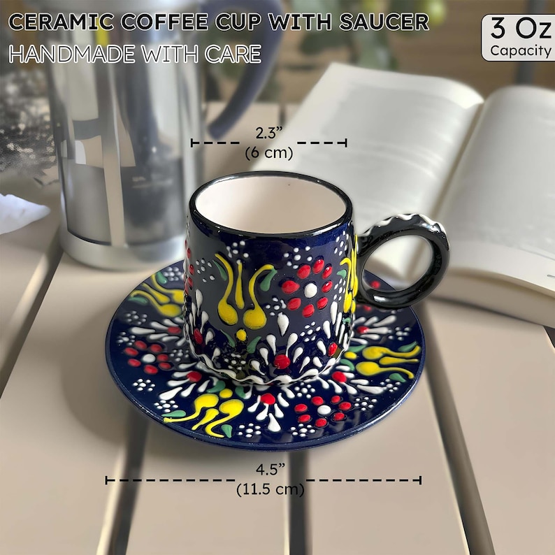 May include: A ceramic coffee cup and saucer set. The cup and saucer are navy blue with a colorful floral pattern. The cup is 2.3 inches (6 cm) in diameter and the saucer is 4.5 inches (11.5 cm) in diameter. The set is handmade and holds 3 oz.