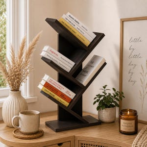 May include: A dark brown wooden tree-shaped bookshelf with multiple angled shelves holding various books including Atomic Habits, Sapiens, and Deep Work. The structure features a central vertical support with branches extending to hold books.