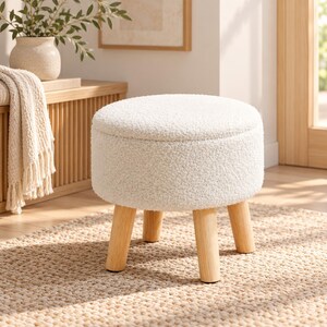 May include: A round ottoman featuring a white textured sherpa fabric upholstery and four light-toned wooden legs. The stool has a cylindrical shape with a flat top surface and a sturdy base, providing a simple and functional seating option.