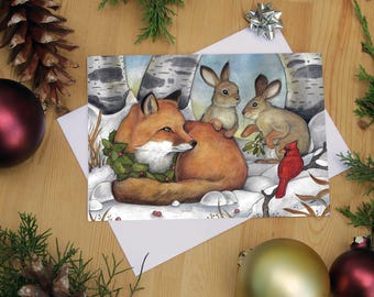 May include: A Christmas card depicting a fox wearing a holly wreath, two rabbits, and a red cardinal in a snowy forest. The card is accompanied by a white envelope and festive decorations.