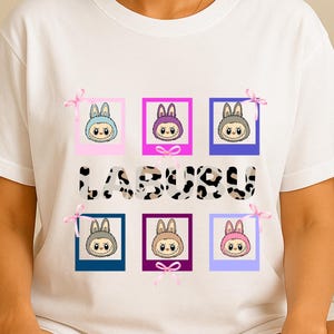 Kawaii Labubu T-shirt with six colorful framed faces, pink bows, and bold cow-print lettering, cute gift idea for fans and collectors