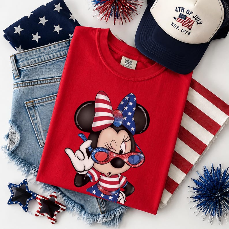 Może przedstawiać: Czerwona koszulka z Minnie Mouse w patriotycznym stroju, w tym kokarda, okulary przeciwsłoneczne i sukienka w gwiazdy i paski. Obraz zawiera r&oacute;wnież dżinsowe szorty, czapkę z daszkiem z napisem "4th of July" i okulary przeciwsłoneczne w kształcie gwiazd.