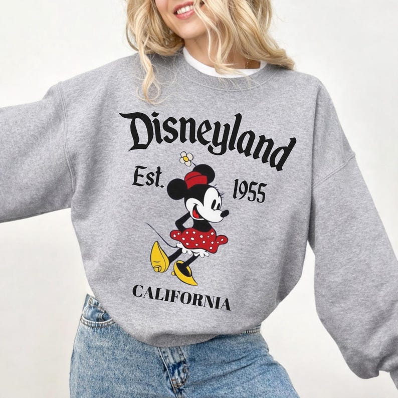 May include: A grey sweatshirt with the Disneyland logo, the text "Est. 1955" and "California." The graphic features a cartoon Minnie Mouse in a red polka dot dress and yellow shoes.