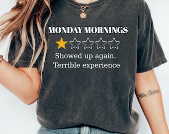 May include: Dark gray t-shirt with the text "MONDAY MORNINGS" and a rating of one gold star out of five. The shirt also says "Showed up again. Terrible experience."