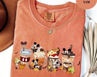 Può includere: Una maglietta Comfort Colors color igname con una grafica di personaggi di Topolino con bevande al caffè a tema autunnale. La maglietta include una collana d'oro e un'etichetta che dice "Comfort Colors".