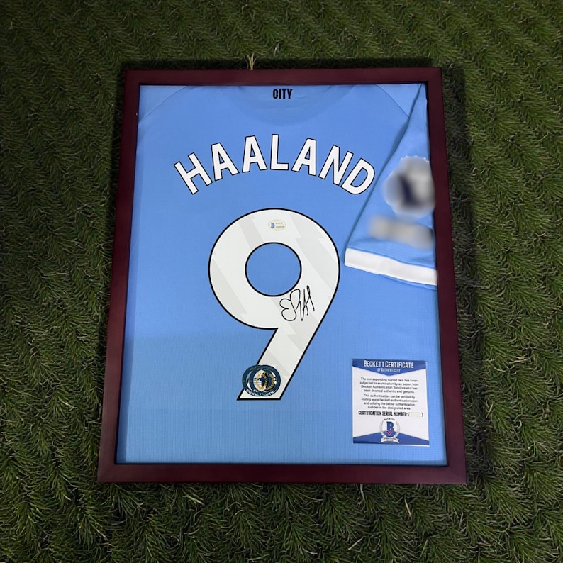 Pu&ograve; includere: Maglia azzurra incorniciata con il nome "HAALAND" e il numero "9" in bianco. La maglia &egrave; firmata e include un'etichetta "BECKETT CERTIFICATE". La cornice &egrave; di colore marrone scuro.