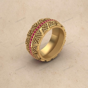 May include: A gold-colored ring with intricate openwork and a row of small, red gemstones. The ring features a detailed pattern of interwoven shapes and a polished interior, showcasing a classic design.