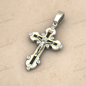 May include: A silver pendant in the shape of a cross, featuring a detailed depiction of Jesus Christ. The cross has black and gold accents, with clear gemstones. The pendant is designed with a loop for a chain.