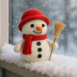 May include: A crocheted snowman wearing a red hat and scarf, with black button details and a carrot nose. It holds a small broom. The snowman is set against a snowy backdrop, evoking a winter scene.