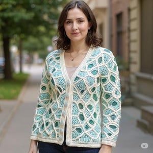 May include: A light blue and cream crochet cardigan featuring a geometric design and light blue buttons. The V-neck cardigan has long sleeves. The woman in the image is wearing the cardigan.