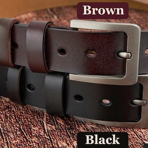 May include: Close-up of two leather belts, one brown and one black, with silver-coloured rectangular buckles. The brown belt is labelled "Brown" and the black belt is labelled "Black". The belts are on a textured brown surface.