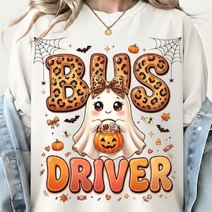 Puede incluir: Una sudadera blanca con el gráfico de un fantasma con un lazo de estampado de leopardo, sosteniendo un cubo de calabaza para dulces. El texto BUS DRIVER está impreso en letras naranjas grandes, con BUS en estampado de leopardo. Incluye murciélagos.